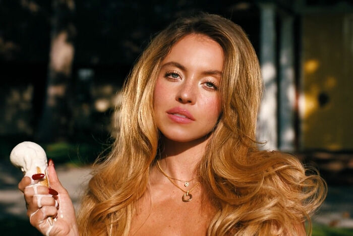 Young woman with long blonde hair holding a dripping white substance, illustrating sploshing in the bedroom concept.