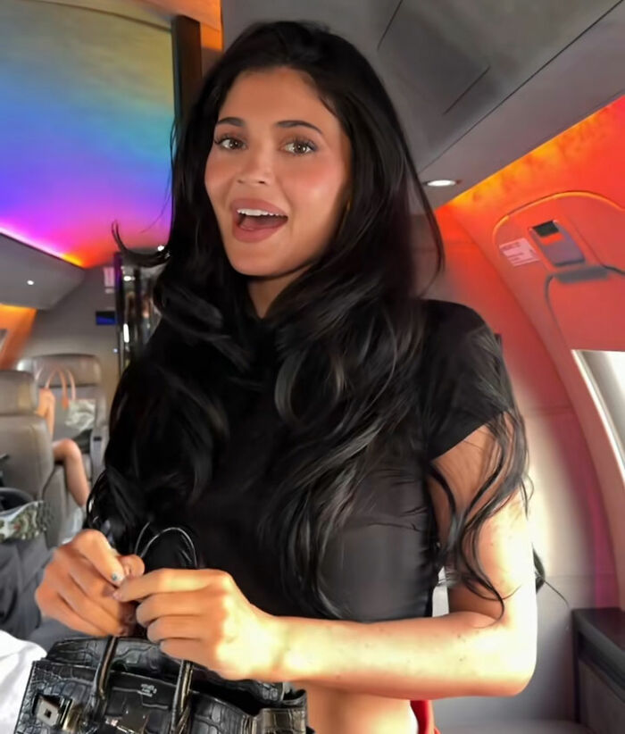 Kylie Jenner dentro de um jato particular com iluminação interna colorida, ligada à reação distópica da turnê da casa Coachella.