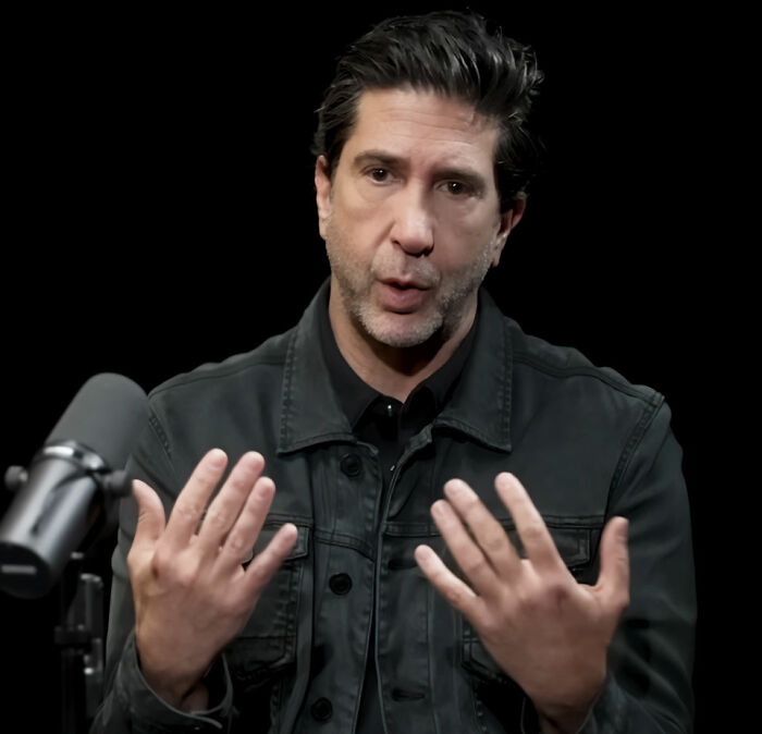 Homem de jaqueta preta falando em um microfone, relacionado às consequências do festival sem fio de Kanye West e retirada do patrocinador.