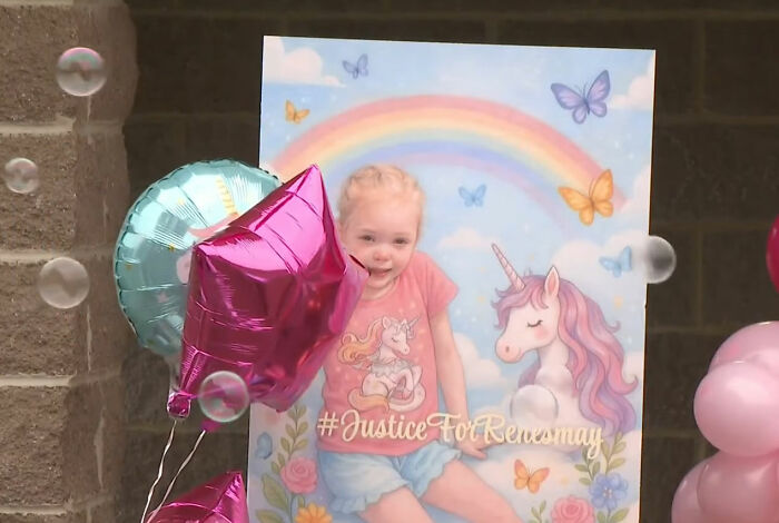 Um grande banner mostrando uma menina de 4 anos, Renesmay, com unicórnios e arco-íris, cercada por balões e bolhas. Nele está escrito #JusticeForRenesmay, destacando o caso de desaparecimento de uma criança de 9 anos.