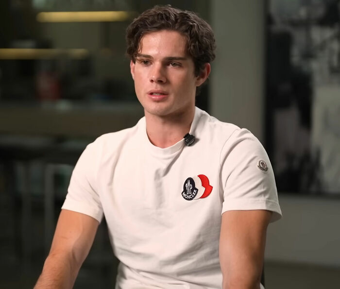 Looksmaxxer in a white shirt speaking during an indoor interview about a recent disturbing livestream incident.