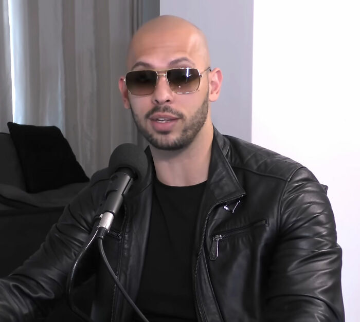 Looksmaxxer wearing sunglasses and a leather jacket speaking into a microphone during a livestream session.