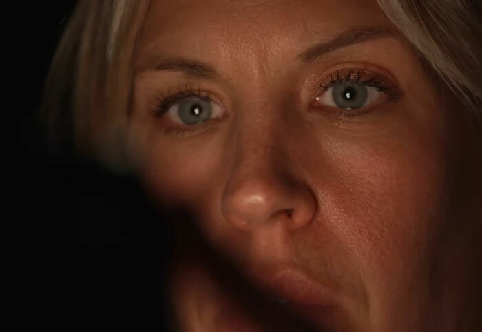 Close-up of a concerned woman&rsquo;s face illuminated in darkness, highlighting investigation into crimes against wives website.