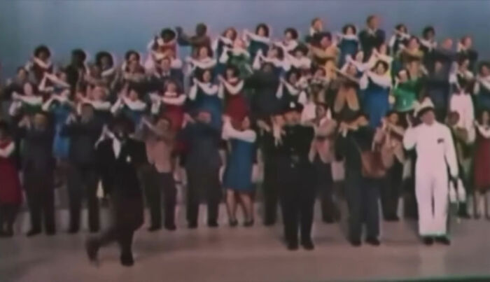 Large group of people posing in a staged setting, illustrating stories about moms shared by 75 people.