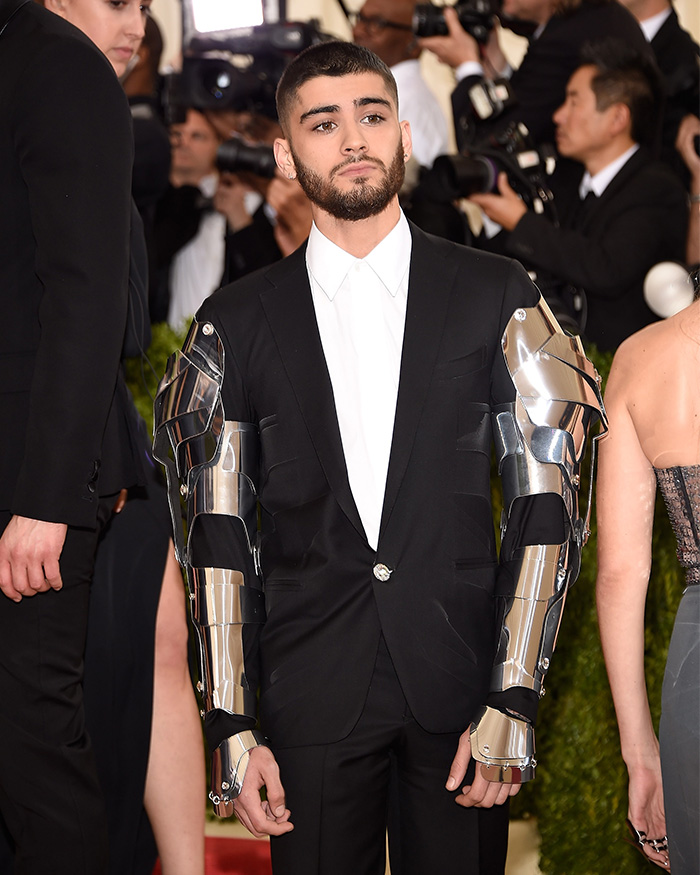 Zayn Malik at the Met Gala, wearing a black suit with armored sleeves, looking bored. Celebrities who hated the Met Gala.