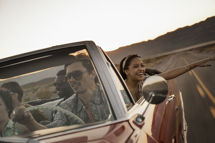 Happy friends in a convertible on a desert road, showing their cheat codes for surviving adult life.