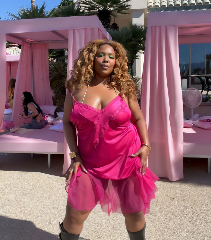 Woman in bright pink dress posing outdoors at Coachella with pink cabanas in the background, showcasing fashion fails and absurd looks.