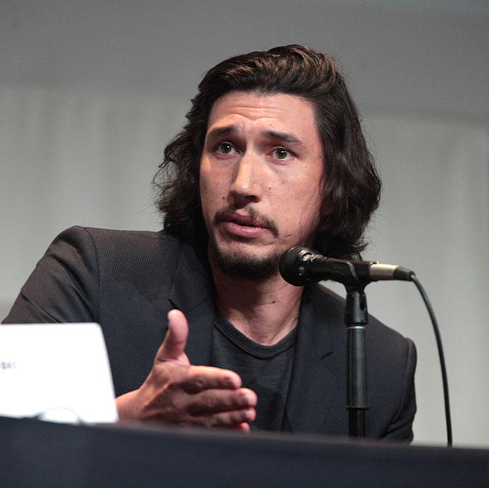 Adam Driver speaking at a panel, wearing a dark blazer, discussing topics related to Lena Dunham and Girls set accusations.