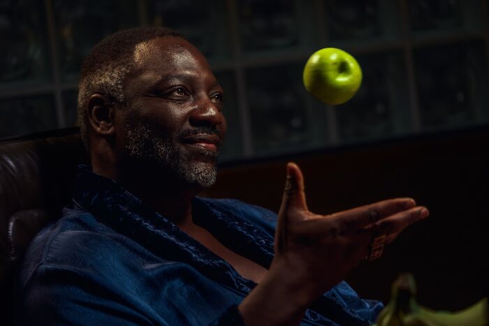 Homem em um quarto escuro jogando uma maçã verde, relacionado ao criador de Euphoria enfrentando reação negativa em cena ofensiva.