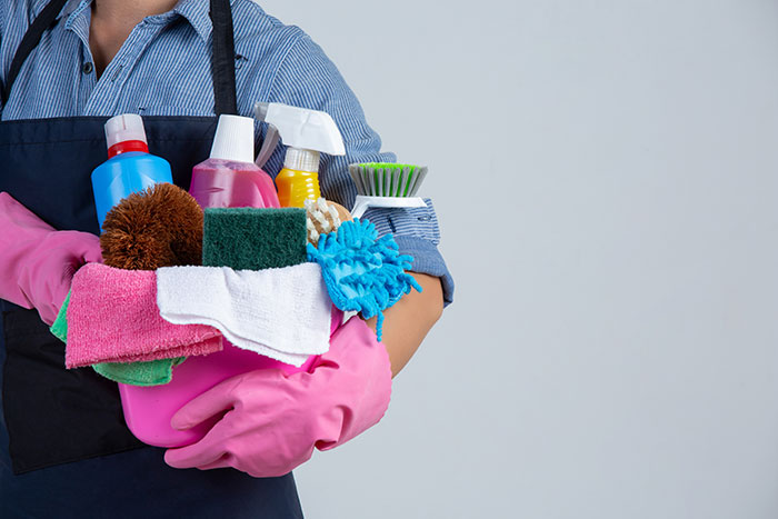 Person wearing pink gloves holding cleaning supplies, visualizing the regret of bringing home a senior cat with tapeworms.