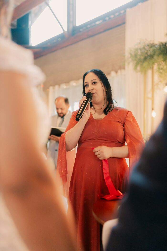 Woman in orange dress speaking into microphone at a wedding ceremony, illustrating trashy tacky and distasteful wedding stories.