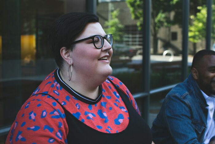 Person smiling outside with glasses and hoop earrings, representing stories about former bullies and kids being evil.