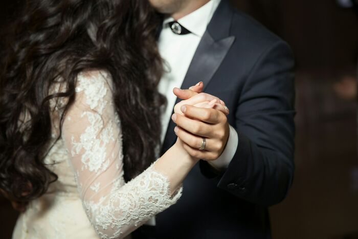 Bride and groom holding hands while dancing at a wedding, guests witnessing signs of a future breakup.