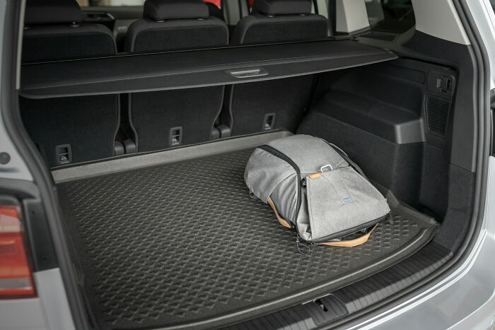 Open car trunk with a gray backpack inside, illustrating adults sharing dumbest childhood moments showing no survival instincts.