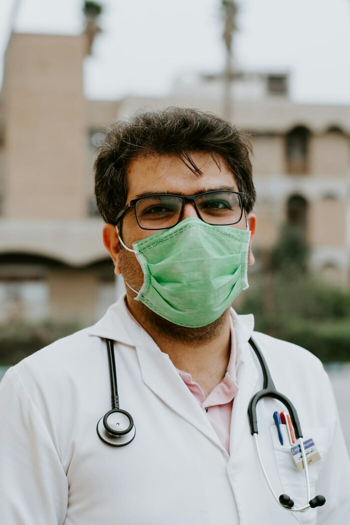 A doctor wearing glasses, a green face mask, and a stethoscope, symbolizing health and resilience. God Bless America.
