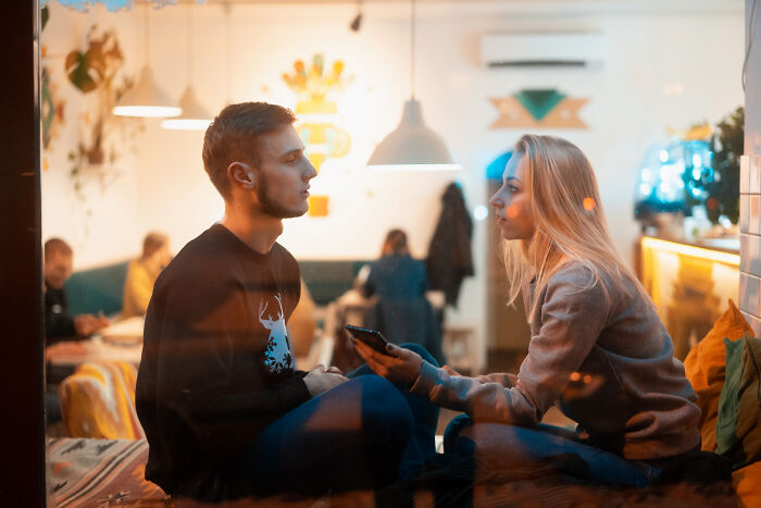 A couple on a first date, captured through a window, showing slight tension or reflection. This scene could be a character-building trauma.