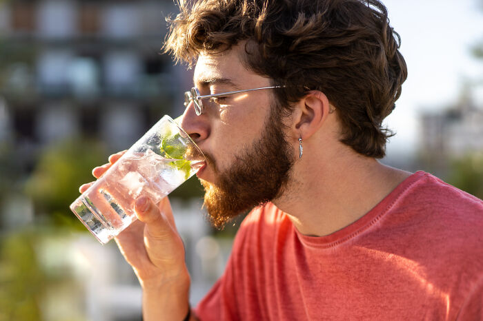 Man with glasses and a beard drinking a cocktail, representing a juicy confession or group therapy session.