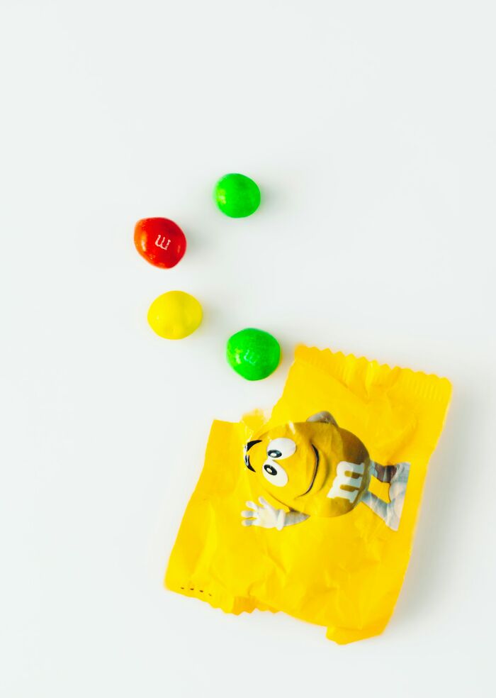 Colorful M&M candies spilling from a yellow wrapper, symbolizing bright and interesting stories about moms.