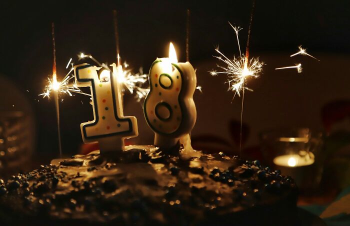 Birthday cake with number 18 candles and sparklers lit, representing tips and tricks parents share for celebrations.
