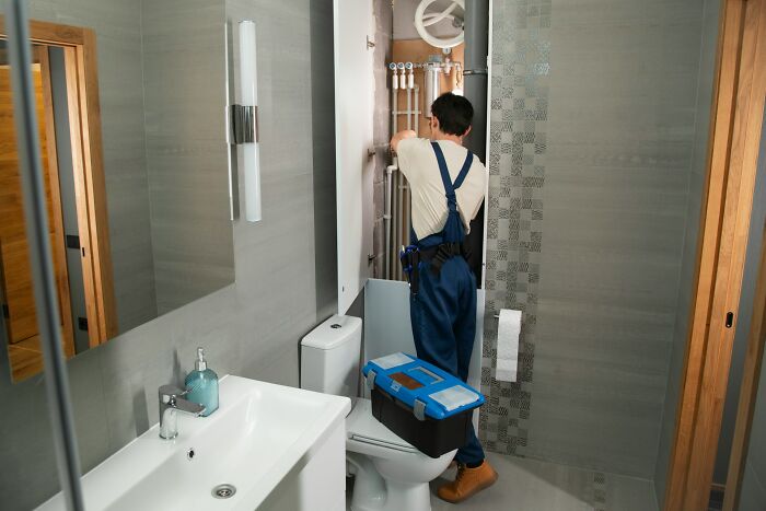 Plumber fixing pipes in a modern bathroom, demonstrating jobs that AI can’t touch in building and maintenance.