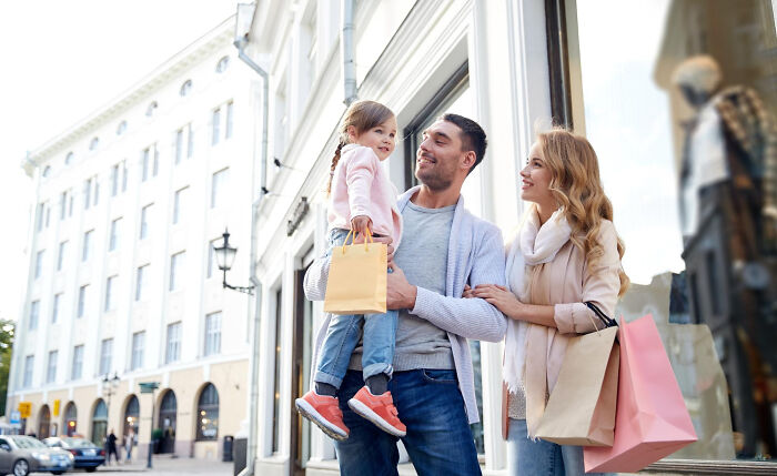 Family outing with parents and child holding shopping bags, illustrating real life plot twists and surprising family connections.