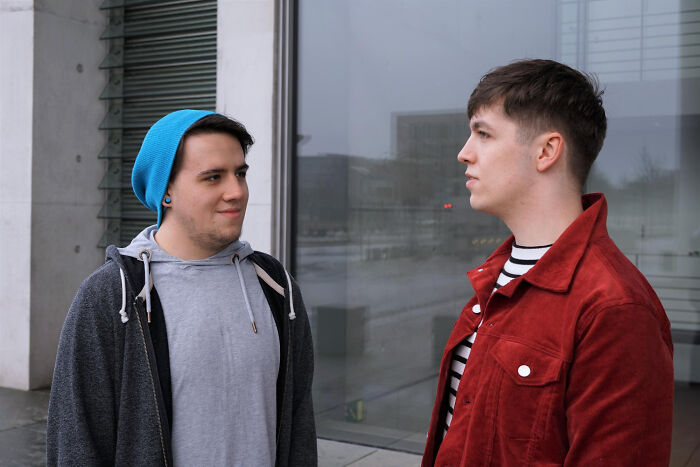 Two young men having a conversation outdoors, illustrating real life plot twists involving family relationships.