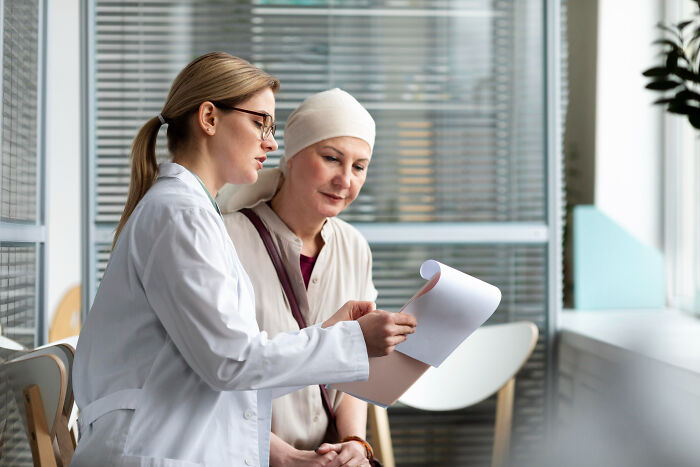 Doctor explaining medical results to female patient wearing headscarf, depicting real life plot twists in family relationships.