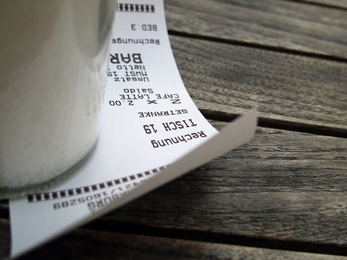 Receipt on a wooden table next to a cup, illustrating rude customers who learned the hard way not to mess with staff.