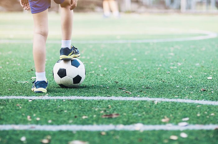 Child standing on soccer ball on green turf, illustrating unexpected truths behind urban legends in sports.
