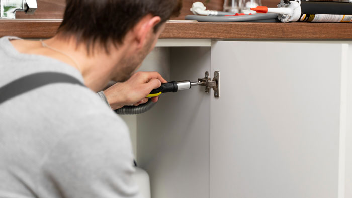 Man installing a hidden dangerous trap inside a kitchen cabinet, highlighting a tense and risky home situation. Man installing a hidden dangerous trap inside a kitchen cabinet, highlighting a tense and risky home situation.