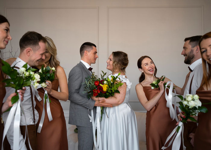 Bride and groom holding a bouquet during a small wedding ceremony surrounded by bridesmaids and groomsmen.
