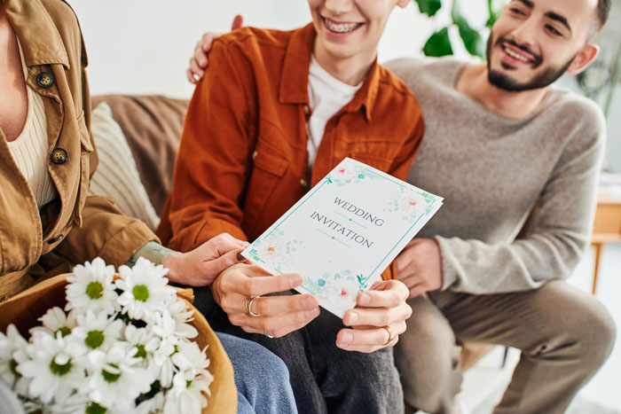 Couple reviewing a wedding invitation together, woman smiling while the man looks on with affection during a casual moment.