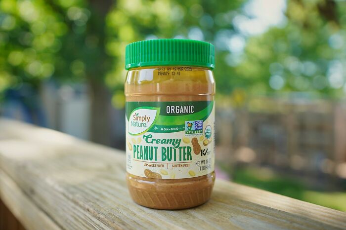Jar of creamy peanut butter on wooden railing outdoors, an example of unusual items TSA has confiscated.