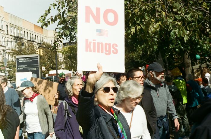Crowd of people marching outdoors, with a woman holding a sign, illustrating stories shared about amazing and interesting moms.
