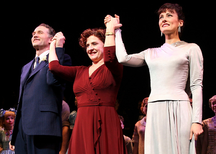 Broadway star on stage wearing vintage costumes, holding hands during curtain call after a theater performance.