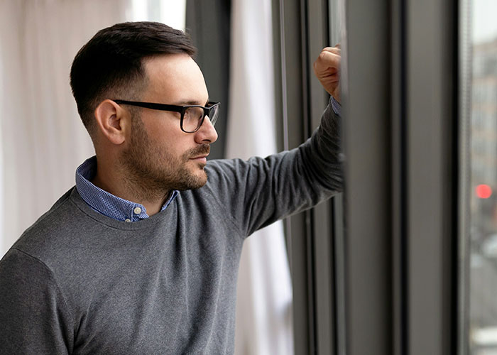 Man in glasses looking out window pensively, reflecting on best friend working as a server and social views. Man in glasses looking out window pensively, reflecting on best friend working as a server and social views.