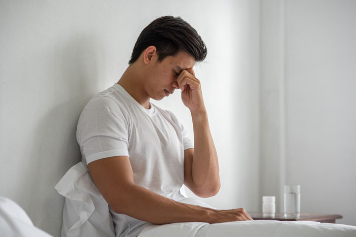 A man in a white shirt sits, looking stressed with his hand on his forehead, a worried dad. A man in a white shirt sits, looking stressed with his hand on his forehead, a worried dad.