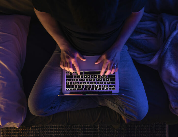 Man typing on laptop at night uncovering depraved website giving men advice on committing horrible crimes against wives.