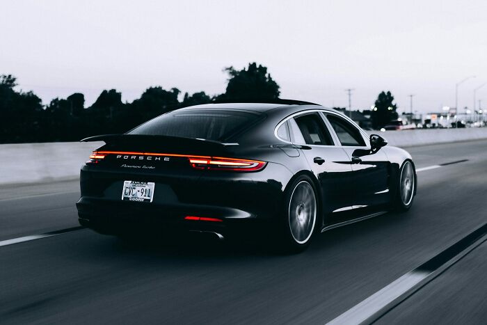 Black Porsche Panamera driving fast on highway at dusk illustrating urban legends that were unexpectedly true on the road.