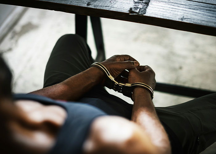 Person in handcuffs sitting at a table, illustrating police chasing the wrong person in an arrest scenario.