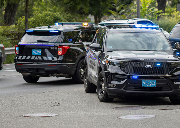 Two police vehicles with flashing lights parked on a street during a police chase involving the wrong person.