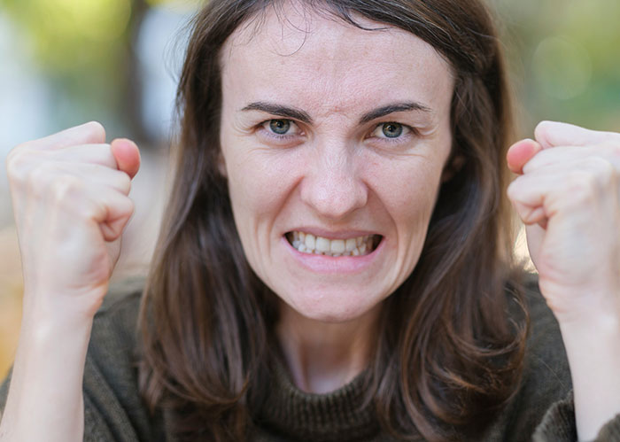 Angry woman with clenched fists outdoors illustrating funny scary wild stories about police chasing the wrong person.