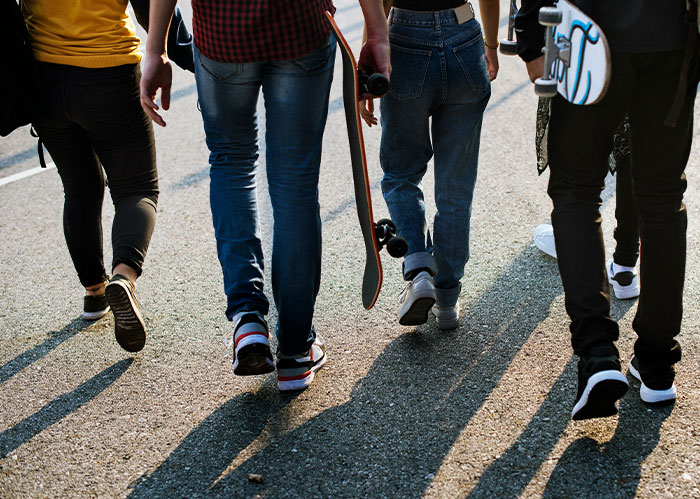 Group of young people walking on pavement, two carrying skateboards, representing stories about police chasing the wrong person.