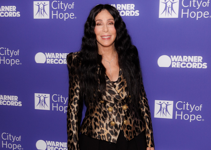Cher participando de um evento da Cidade da Esperança, vestindo um blazer com estampa de leopardo, relacionado à descoberta de notícias secretas da neta.