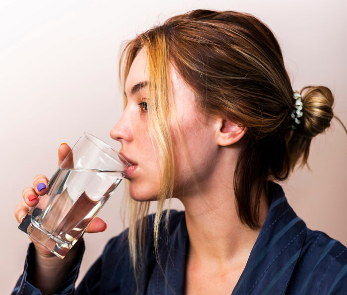 Young woman with colorful nails drinking water, symbolic image for investigation uncovering depraved website advice crimes against wives