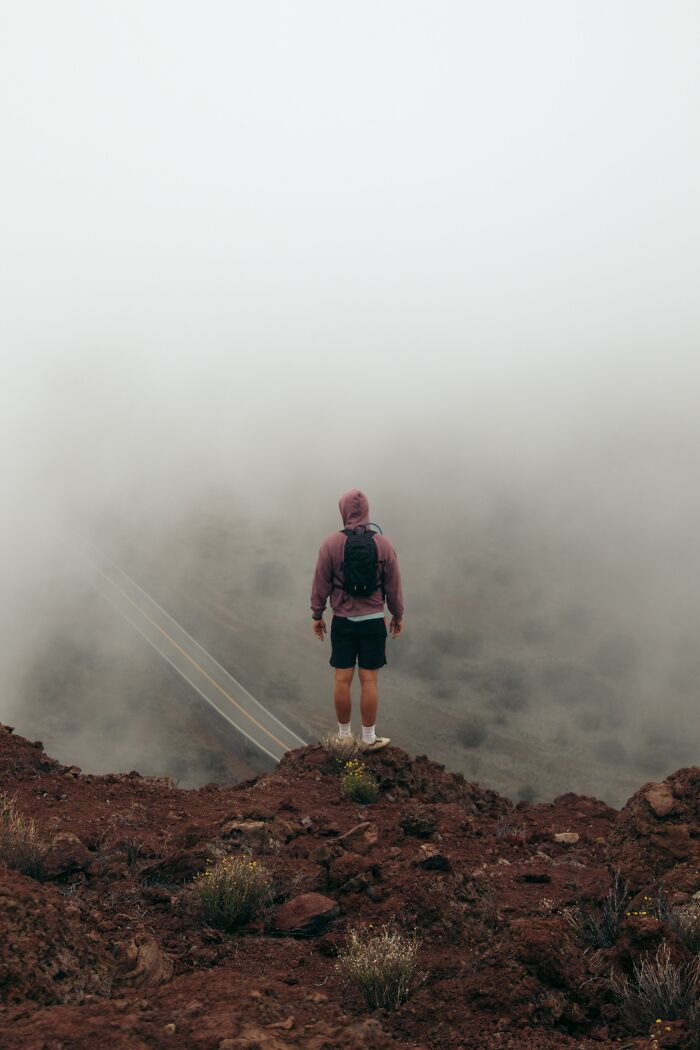 Person standing on rocky cliff in foggy landscape, illustrating unexpected and bizarre ways people passed away.