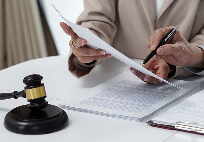 Person reviewing paternity case documents related to identical twins pregnancy with a legal gavel on the table.