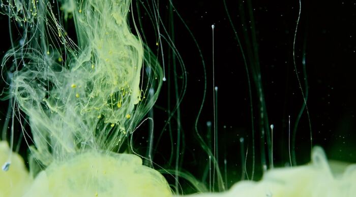Abstract green and yellow ink swirling underwater, illustrating the concept of science and myth quiz.