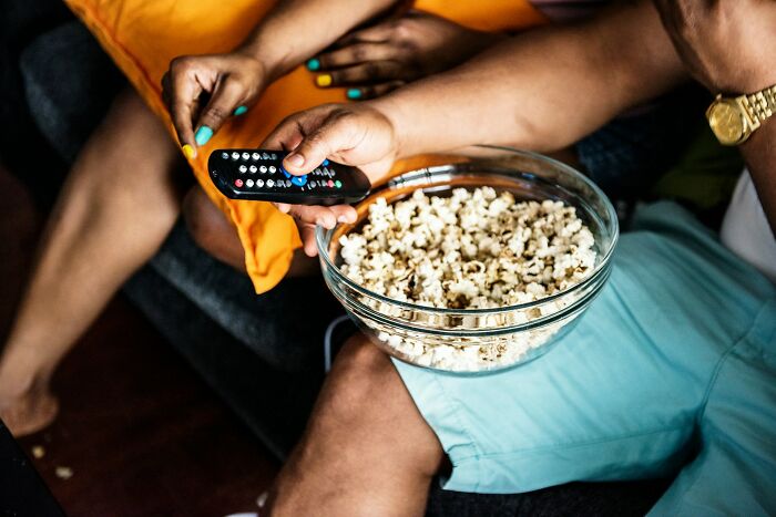 Family watching TV together with popcorn, highlighting normal things people did with their families that now seem bizarre.