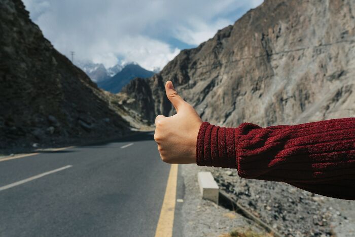 Person with thumb out hitchhiking alone on a mountain road symbolizing kids with no survival instincts.